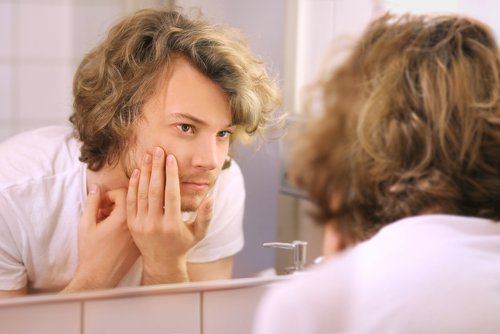 Man popping a pimple on his face